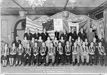 A vintage black-and-white photograph of officers and delegates of the Order Sons of Italy in America at the first Washington State Convention on November 10, 1930. The group is posed in a hall with American and Italian flags displayed in the background.